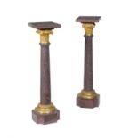 A pair of French porphyritic stone and gilt bronze mounted pedestal columns