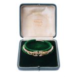 An Edwardian 15 carat gold, sapphire and half pearl bangle