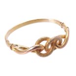 A gold coloured knot hinged bangle