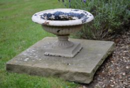 A pair of small white painted cast iron urns on plinths