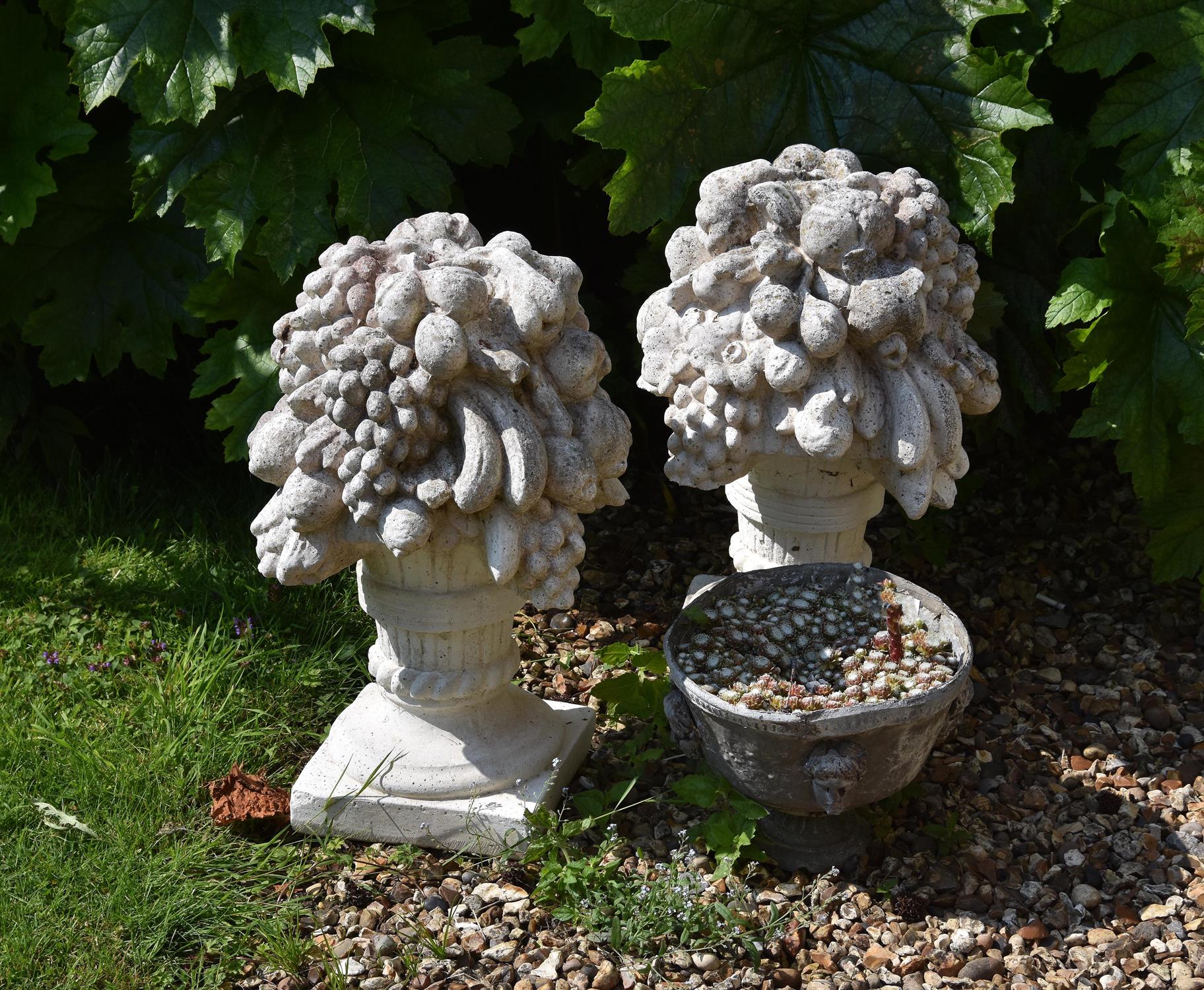 A pair of reconstituted stone finials modelled as fruit and flower vases