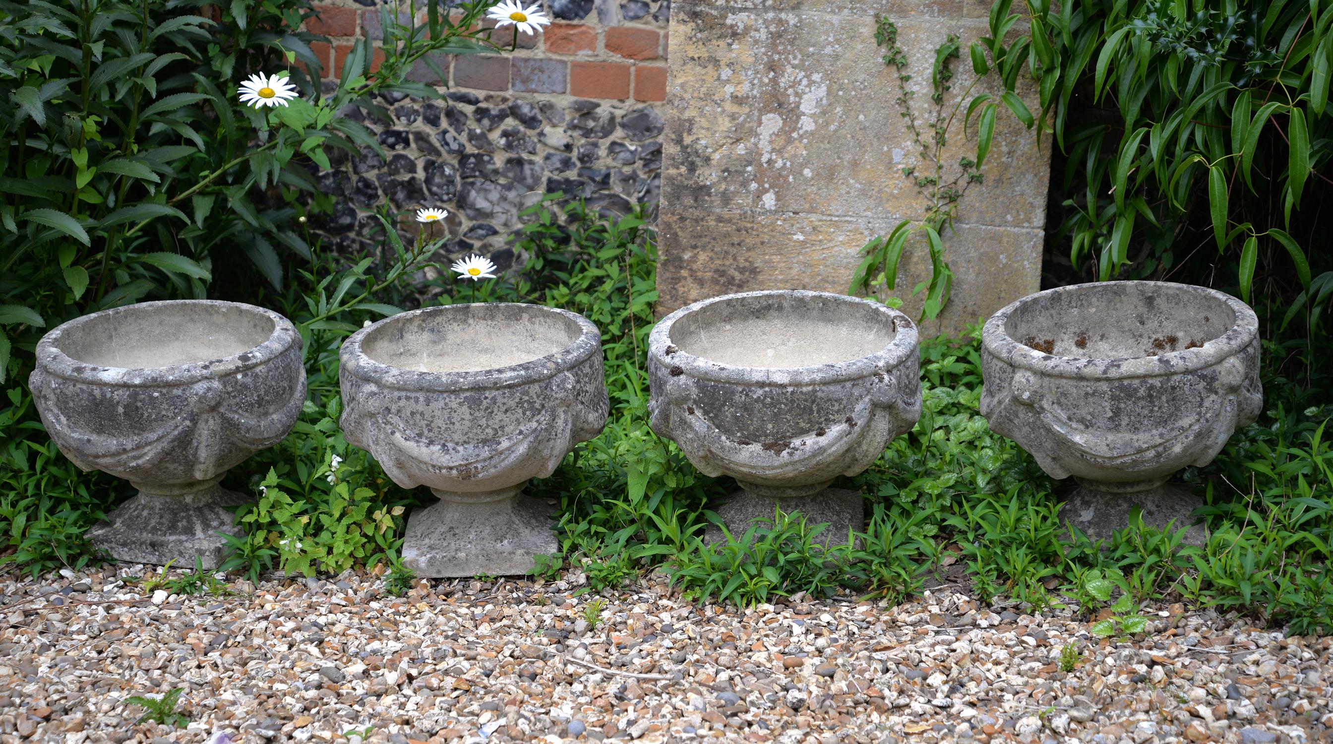 A set of four stone composition garden urns