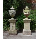 A pair of English limestone and composition urns on plinths