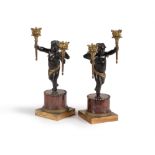 A pair of Restauration patinated and gilt bronze and rouge griotte marble mounted figural candelabra