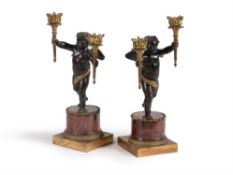 A pair of Restauration patinated and gilt bronze and rouge griotte marble mounted figural candelabra