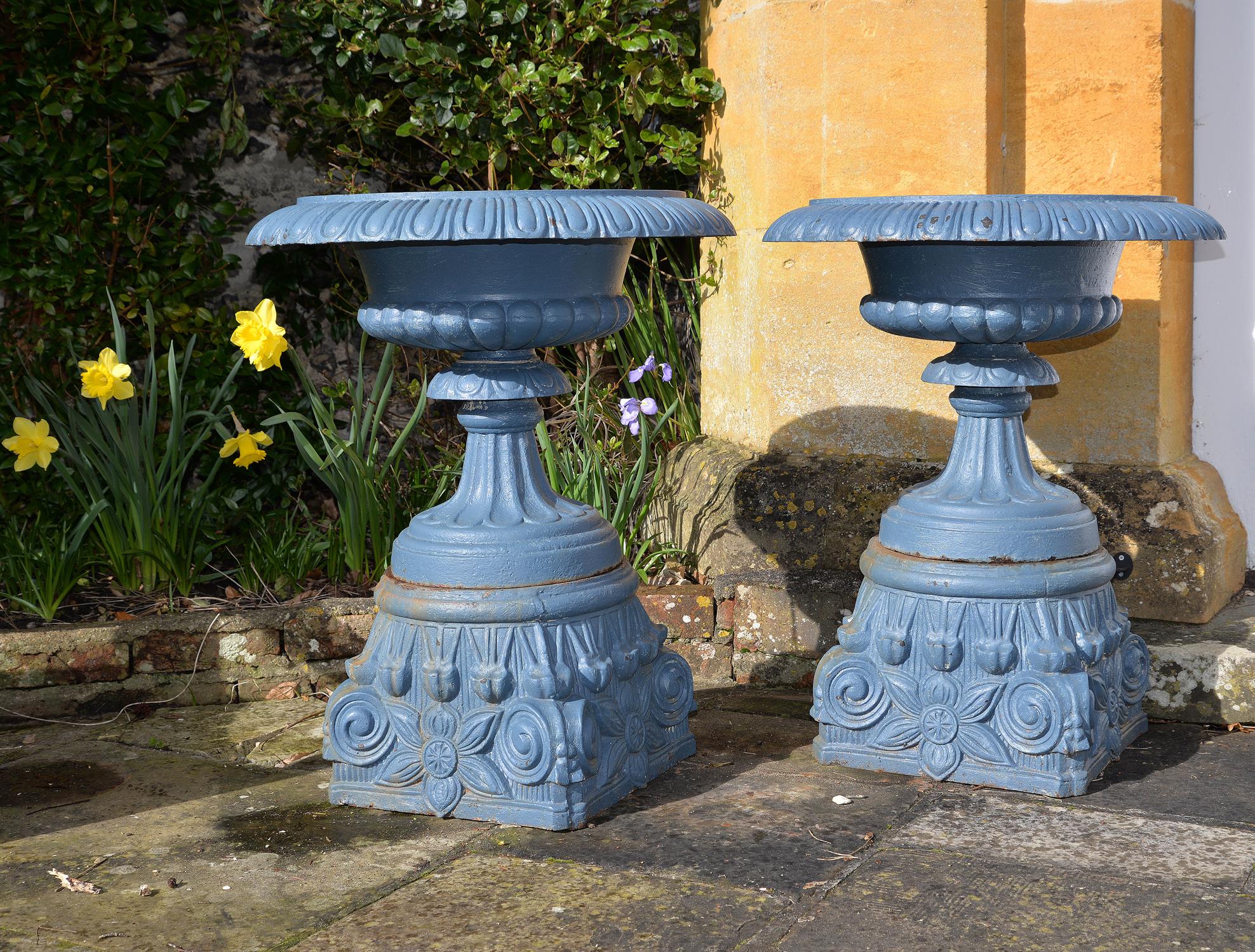 A pair of Victorian blue painted cast iron garden urns on plinths