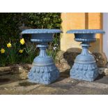 A pair of Victorian blue painted cast iron garden urns on plinths
