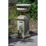 A stone composition garden urn on plinth