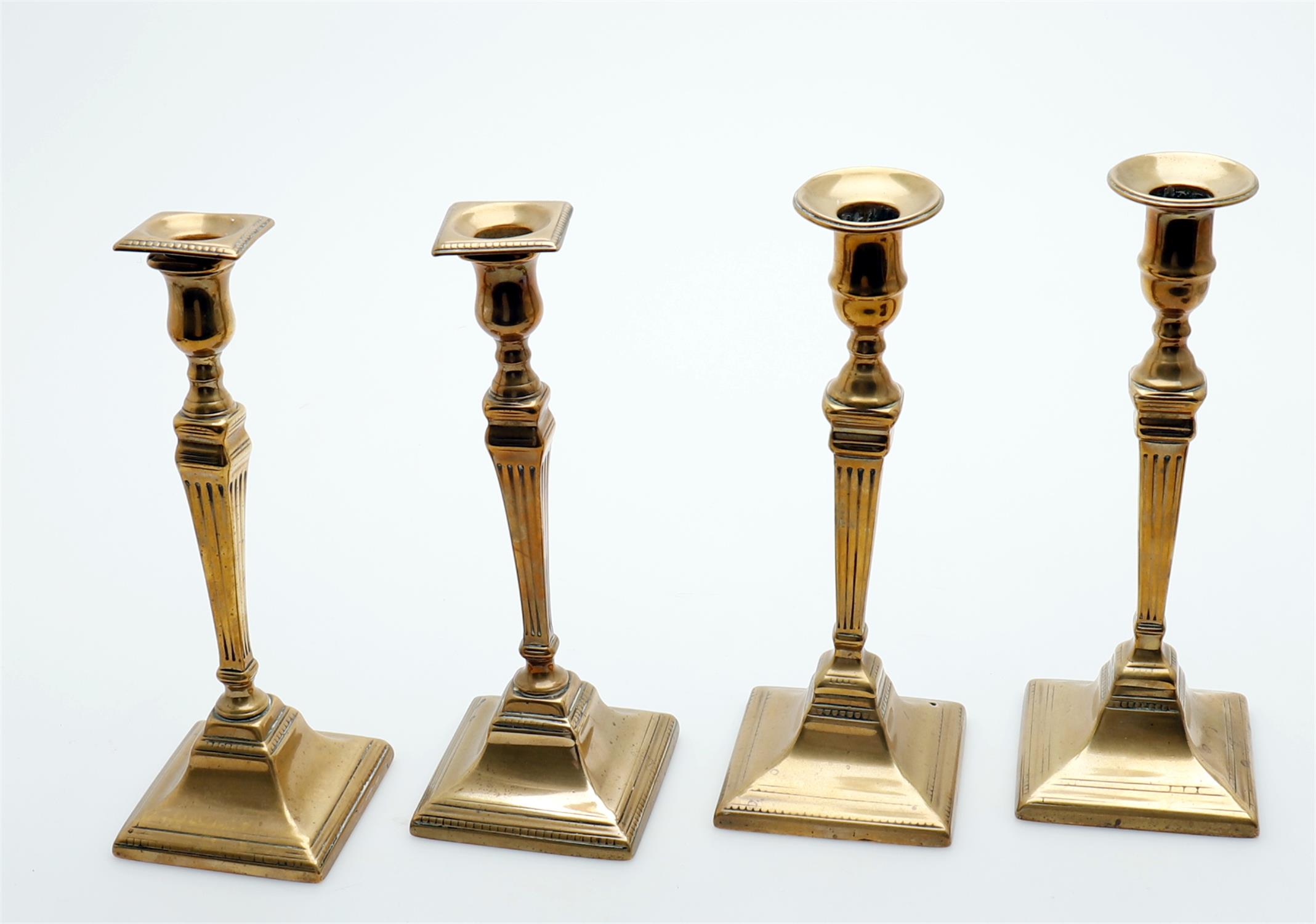 Two pairs of George III brass candlesticks