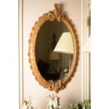 A carved giltwood oval wall mirror in George III style