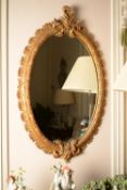 A carved giltwood oval wall mirror in George III style