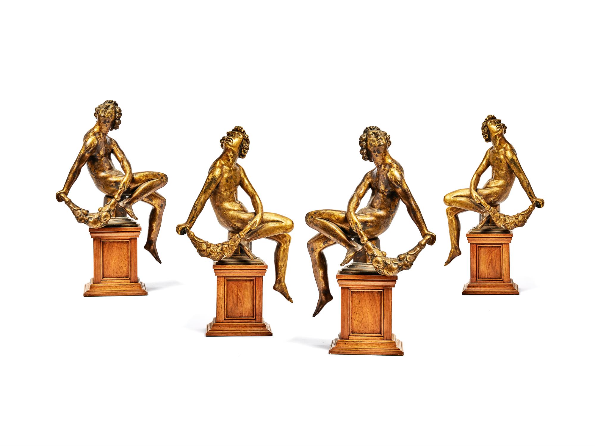 A set of four German gilt bronze alloy models of seated youths