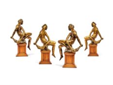 A set of four German gilt bronze alloy models of seated youths