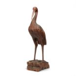 A carved and stained pine model of a standing crane