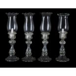A set of four modern clear moulded glass baluster storm lights and floriform shades