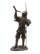Standing bronze figure of a Chinese warrior holding a horn and lance on naturalistic base H48cm
