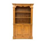 20th century varnished pine bookcase on cupboard, projecting cornice over shaped apron,