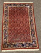 Persian design red ground rug, with repeating herati motif on red field, guarded blue border,