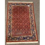 Persian design red ground rug, with repeating herati motif on red field, guarded blue border,