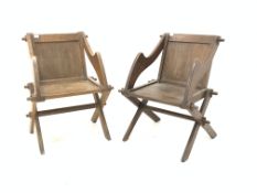 Two similar oak Glastonbury chairs, with panel back and seat, raised on cruciform base,