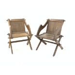 Two similar oak Glastonbury chairs, with panel back and seat, raised on cruciform base,