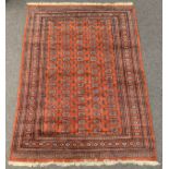Persian design Bokhara ground carpet, repeating gul motif on burnt orange field, guarded border,