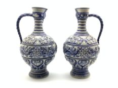 Pair of 19th Century Westerwald stoneware ewers decorated in relief with masks,