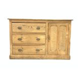 Late 19th century pine sideboard, with three long drawers beside panelled door enclosing one shelf,