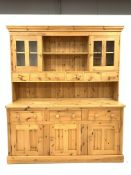 Large solid pine dresser, moulded cornice above two open shelves, two glazed doors and six drawers,