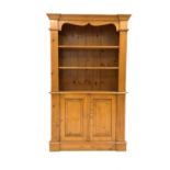 Edwardian varnished pine bookcase on cupboard, projecting cornice over shaped apron,