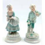 Pair of 19th Century porcelain male and female figures each holding a flower on blue lined circular