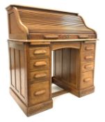 Early 20th century oak twin pedestal roll top desk, tambour front enclosing drawers and cubby holes,