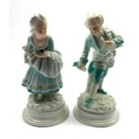 Pair of 19th Century porcelain male and female figures each holding a flower on blue lined circular