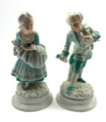 Pair of 19th Century porcelain male and female figures each holding a flower on blue lined circular