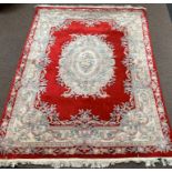 Chinese woolen ground rug, floral medallion on red field, border with scrolled foliate,