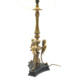 Empire design brass table lamp with three cherubs above a black base, with shade,