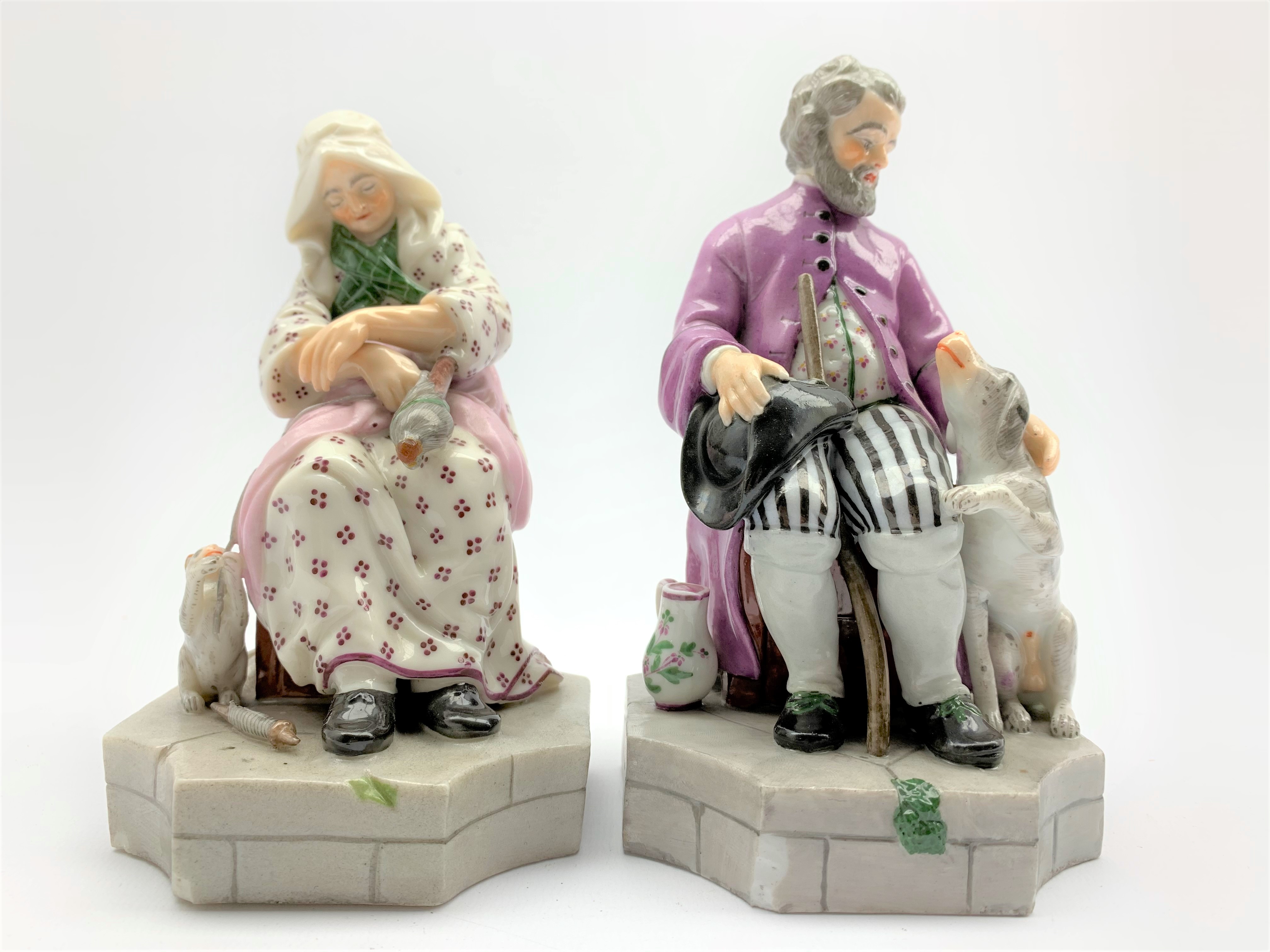 Pair of German seated figures of an elderly man and woman accompanied by a cat and a dog on