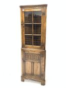 20th century carved oak corner cupboard, dentil cornice over glazed door, panelled door under,