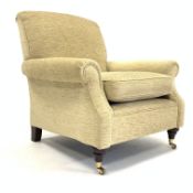 Howard style upholstered armchair, turned mahogany supports and brass cup castors,