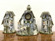Three piece ceramic garniture in the form of a water mill, the centre housing a mechanical clock,