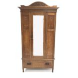 Early 20th century oak wardrobe, arched carved pediment over inlaid panels and mirror door,