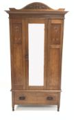 Early 20th century oak wardrobe, arched carved pediment over inlaid panels and mirror door,