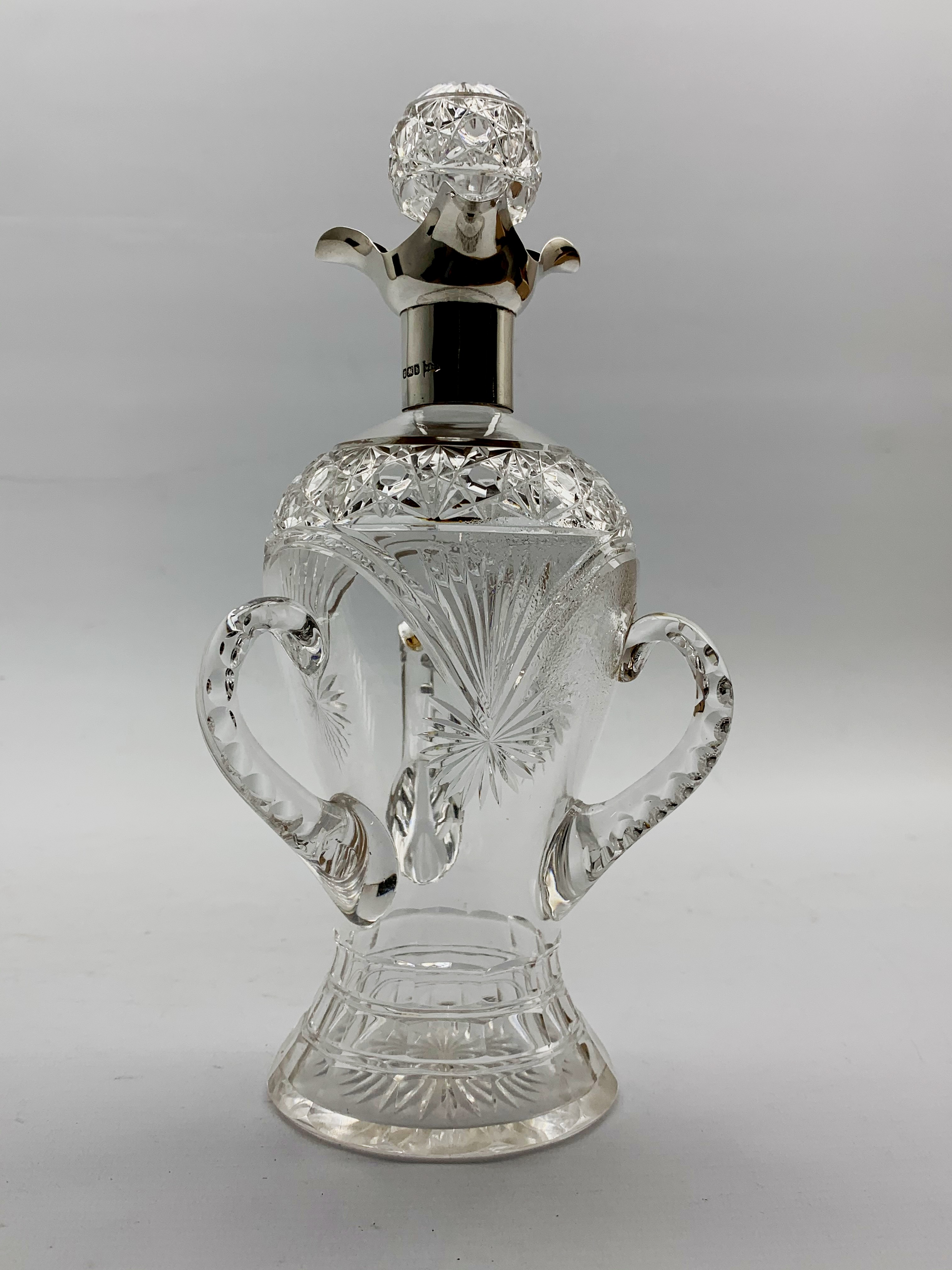 Late Victorian glass decanter of baluster form with three faceted handles,