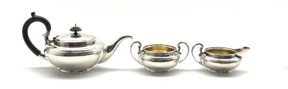Silver three piece teaset of circular form, the teapot with ebonised handle and lift London 1915 Ma
