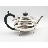 Silver oval teapot of panelled design with ebonised handle and lift on four splay feet Sheffield 193