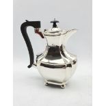 Silver hot water jug of panel sided design with ebonised handle and lift on ball feet H23cm Birmingh