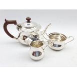 Silver three piece tea set of circular form, the teapot with stained handle and lift Birmingham 1939