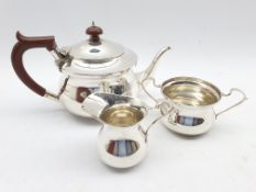 Silver three piece tea set of circular form, the teapot with stained handle and lift Birmingham 1939