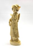 Japanese Meiji carved ivory Okimono of a Bijin, Tokyo School, standing wearing elaborately decorated