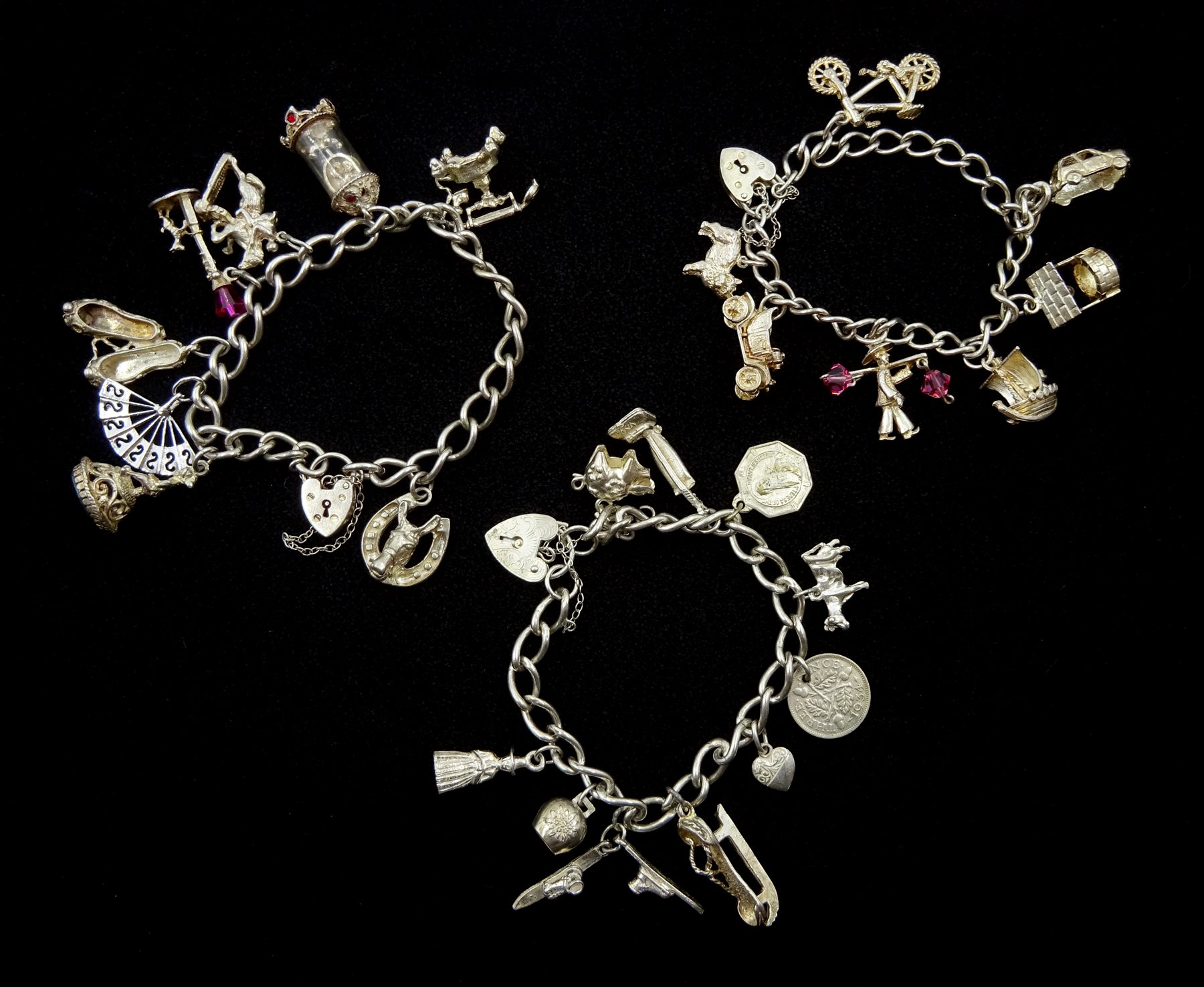 Three silver charm bracelets with various charms including bicycle, Viking ship, clock etc, stamped